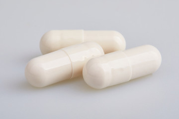 White gelatin capsules with powder, on white background. Pharmaceutical concept.