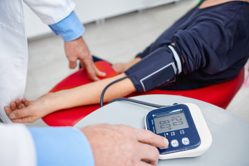 Doctor checking blood pressure with digital monitor 
