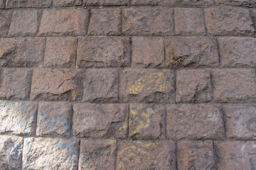 Wall of massive granite blocks for a backdrop. Uneven lighting. Colored spots, relief.