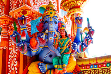 Representation of Hindu gods and tourists climbing a colorful stairs leading to the Batu Caves in...