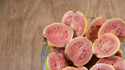 guava (Psidium guajava) fruits in halves in bowl on white background...