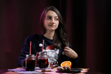 woman in a christmas pullover holding glass of mulled wine and eclair