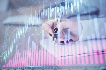 Multi exposure of hands making notes with forex chart huds. Stock market concept.