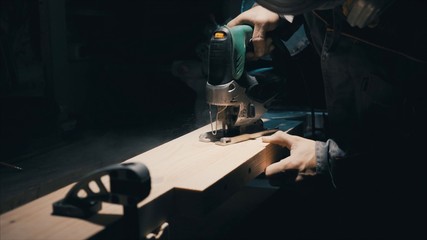 Carpentry workshop in the background, man with an electric jig saw 
