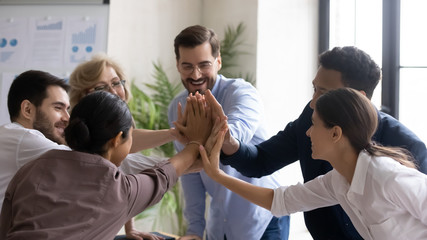Overjoyed multiracial businesspeople give high five celebrate shared business victory or win,...