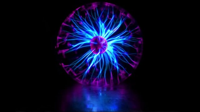 Plasma ball discharge lamp with high voltage lightning. Experiments with an electric Tesla coil and an inert gas discharge tube. Numerous outbreaks and lightning strikes. Abstract background. Looped