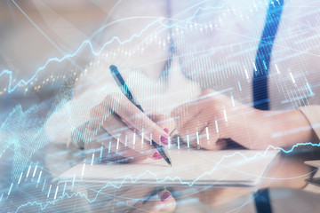 Double exposure of hands making notes with forex chart huds. Stock market concept.