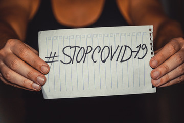 man hands holding a tablet with an inscription #stopcovid-19