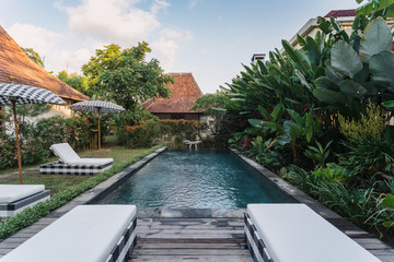 Swimming pool with comfortable rattan deckchairs outdoors at sunny day
