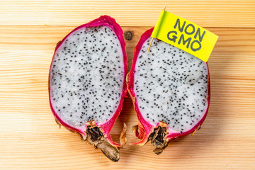Pitaya (dragon fruit) with the inscription non-GMO on a wooden background