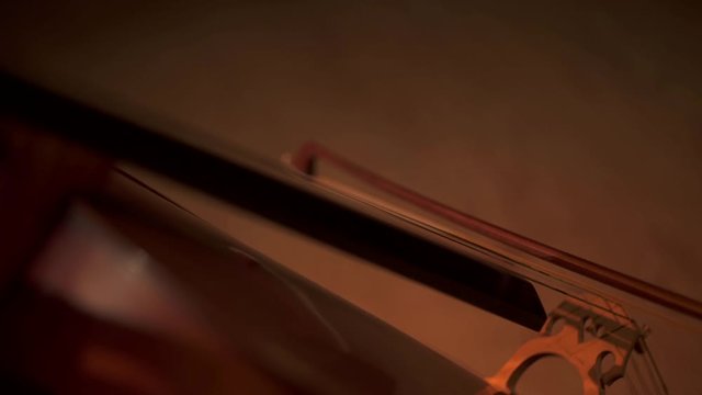 Close up shot of female cello player hands playing cello in concert room. Cello bow.