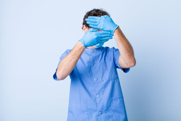 young man covering face with both hands saying no to the camera! refusing pictures or forbidding...