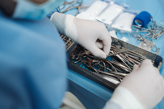 Surgeon prepering a set surgical instruments before surgery.