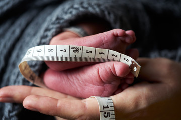 Close-up of the feet of a newborn baby on the palm of a mother.
