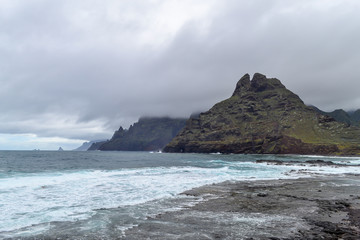 Fototapeta na wymiar View of north of Tenerife, Punta del Hidalgo, Canary island, Spain. Mountain green landscape with ocean coast. Rainy weather and low clouds on the sharp cliffs.