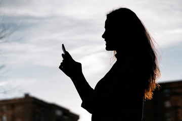 Shadow of a young business woman typing with her phone