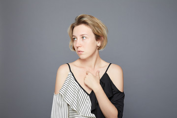 Fototapeta premium Shocked panic blond Caucasian woman excited by unexpected news about virus, keeps mouth opened, startled by breathtaking secret, stares with scared eyes sideways, dressed casually, poses indoors.