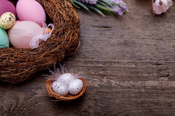 Easter eggs in nest on rustic wooden background.