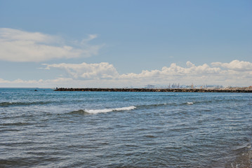 Groyne with people fishing with cranes in the background