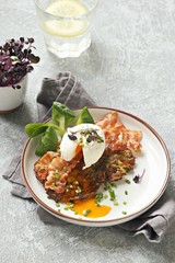 Zucchini fritters with poached egg and fried bacon. Low carb keto breakfast.