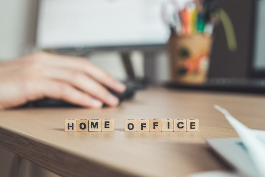 Home Office Concept: “Home Office” Letters In Foreground, Man Working In Home Office In Blurry Background