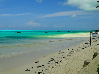 Fototapeta na wymiar Traumkulisse, Fernweh und Karibik feeling am weißen Strand auf Sansibar, mit türkisen Meer und Schäfchenwolken im Hintergrund