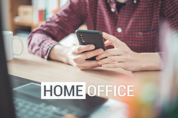 Home office concept: Man is typing on his black mobile phone, Text 