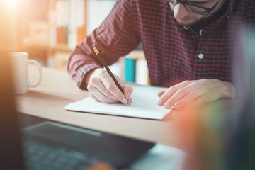 Home office concept: Man writing with a pencil on a white sheet