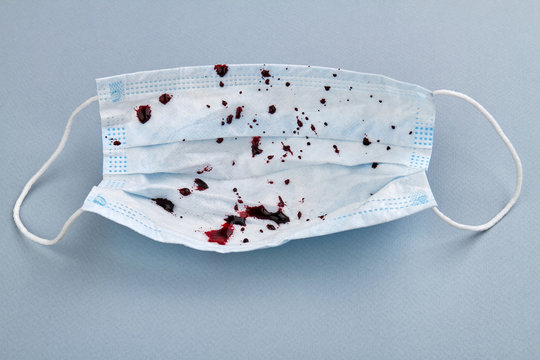 Medical protective mask with blood drops on grey background. Serious respritatory disease. Pneumonia, acute respiratory infections, tuberculosis, lung cancer, hemoptysis or coronavirus.