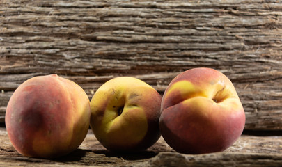 Peach fruits (Prunus persica) in natura on a woody background