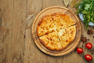 Close up view on tasty traditional Khachapuri - closed baked pie stuffed with melted salt cheese (suluguni) or meat on wooden tray. Traditional georgian food