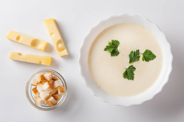 Cheese cream soup with sliced ​​cheese and bread crumbs on a white background