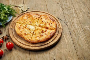 Close up view on tasty traditional Khachapuri - closed baked pie stuffed with melted salt cheese (suluguni) or meat on wooden tray. Traditional georgian food