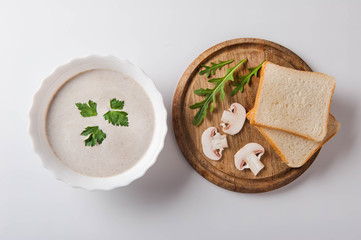 Mushroom cream soup with sliced ​​mushrooms and bread on a white background