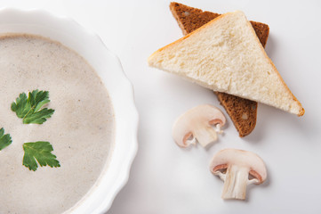 Mushroom cream soup with sliced ​​mushrooms and bread on a white background
