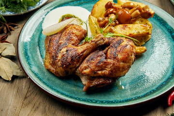 Grilled chicken thighs with baked potatoes and Turkish yogurt sauce on a blue plate on a wooden background. Tasty turkish food