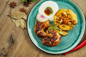 Grilled chicken thighs with baked potatoes and Turkish yogurt sauce on a blue plate on a wooden background. Tasty turkish food