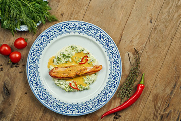 Delicious grilled salmon steak filet with peas in a creamy sauce in a white plate on a wooden background. Tasty seafood
