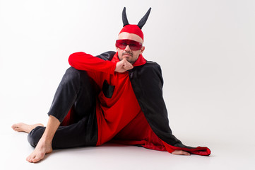 Fashionable man in black red diabolical carnival clothes wearing devil horns and sportive...