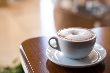 Cup of cappuccino on saucer on wooden table