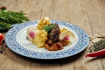 Delicious veal (beef) cheeks with honey sauce and mashed potato garnish in a blue plate on a wooden background. Close up view