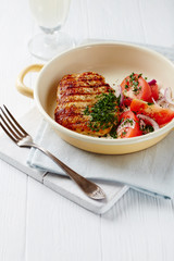 Grilled Turkey Breast with tomatoe salad. Bright wooden background.. Copy space. 