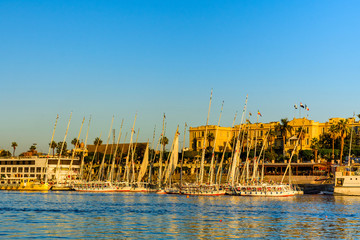 Fototapeta na wymiar Traditional egyptian vessels feluccas and tourist boats moored near the bank of Nile river in Luxor, Egypt