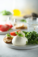 Fresh Burrata cheese with bread, arugula and tomatoes