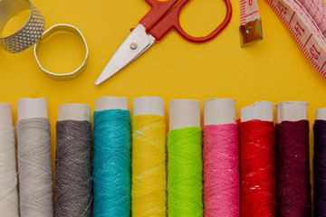 Thread, needles, scissors and meter on yellow background. tailoring set. sewing kit multi-colored.