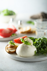 Fresh Burrata cheese with bread, arugula and tomatoes