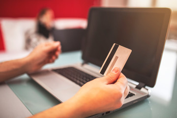 Hands holding credit card and using laptop.