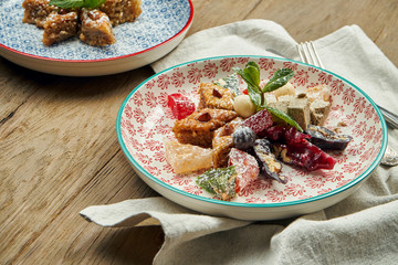 Classic Turkish baklava with pistachios and honey in a ceramic plate on a wooden background. Turkish pastries and sweets. Close up