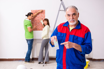 Young couple and old contractor in home renovation concept