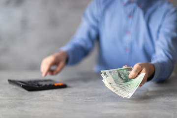 Oferta oszczędności, liczenie na kalkulatorze i plik polskich pieniędzy w dłoni